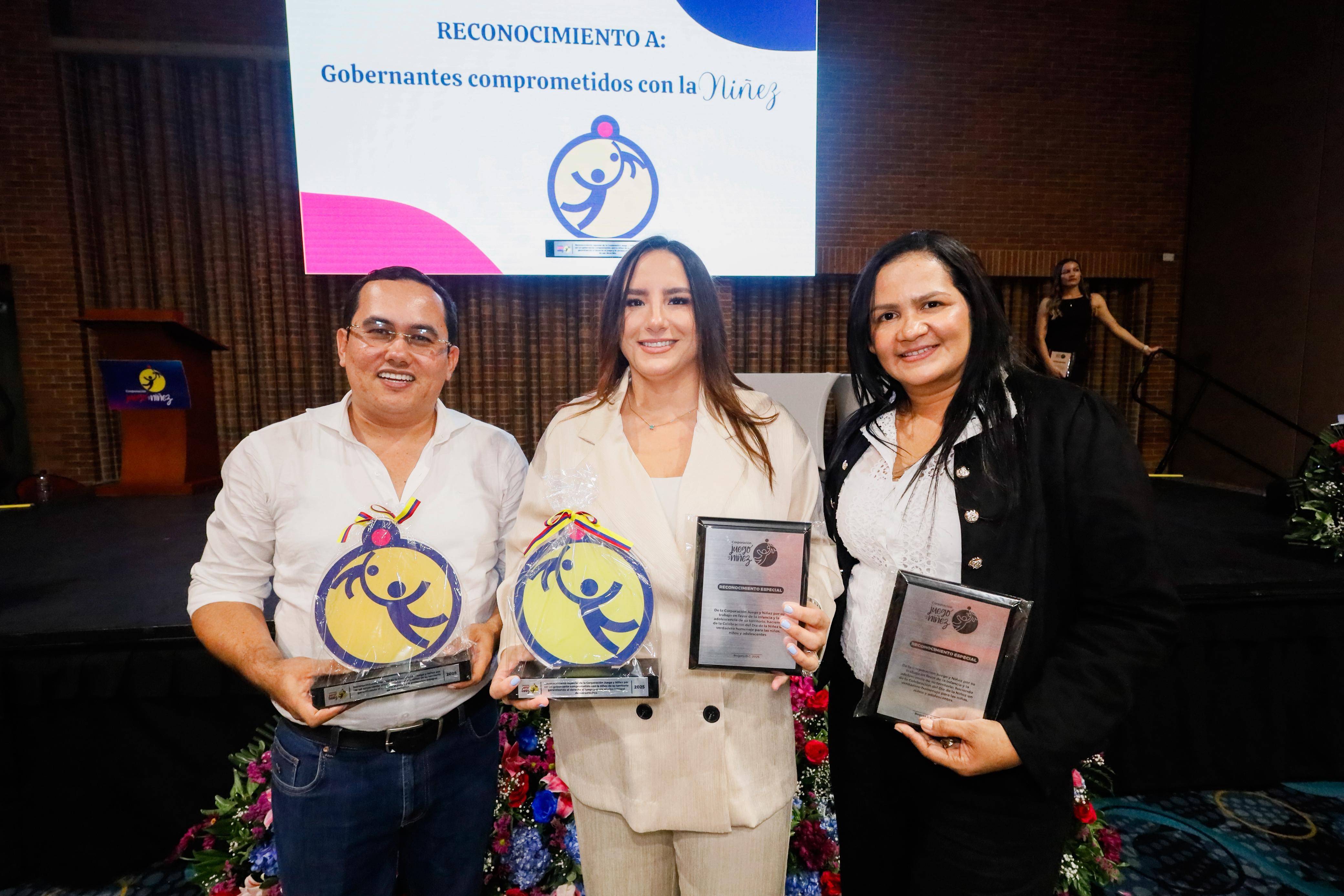 Tres representantes exhiben trofeos y placas durante la premiación