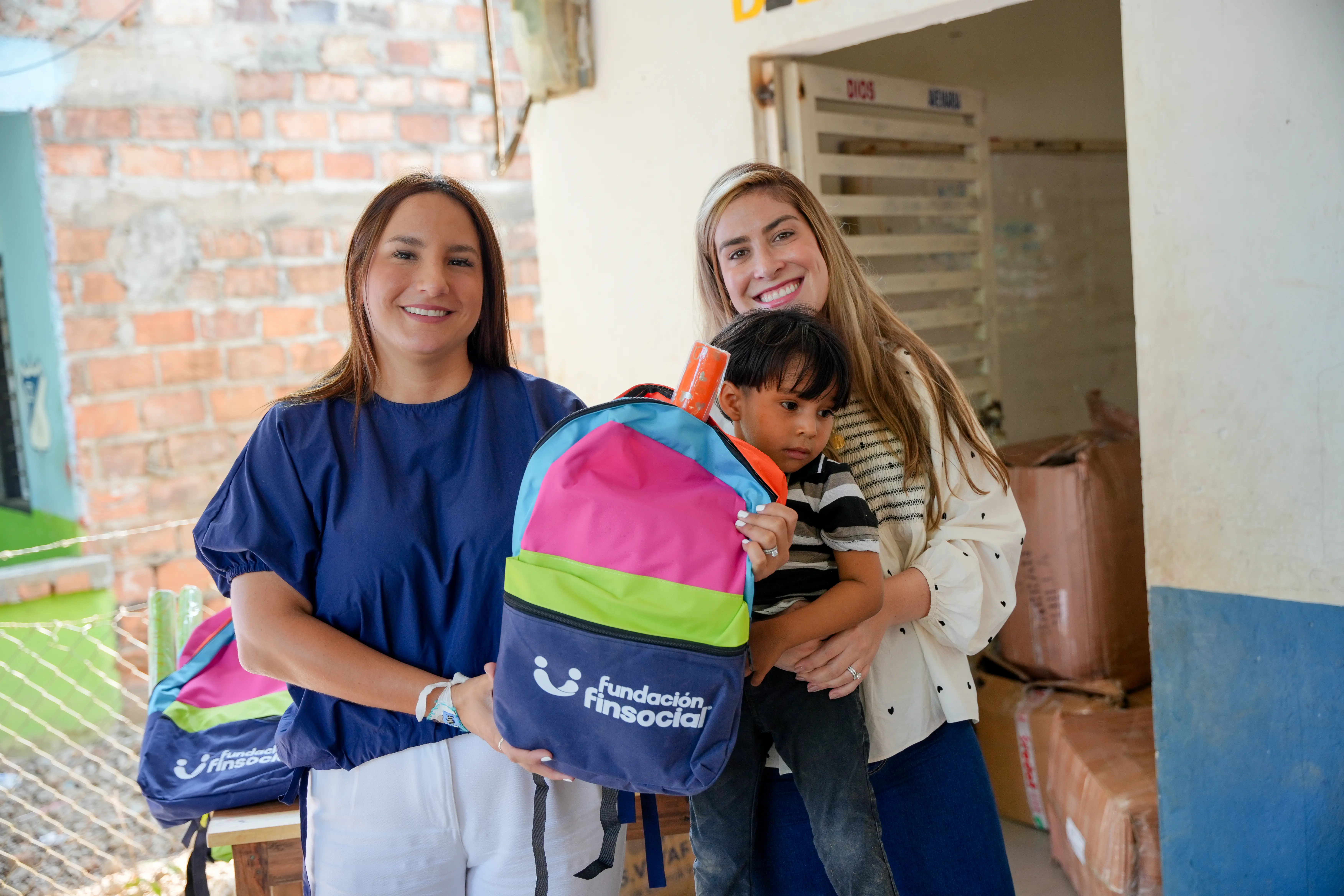 Madre con su bebé recibe un morral escolar junto al equipo institucional