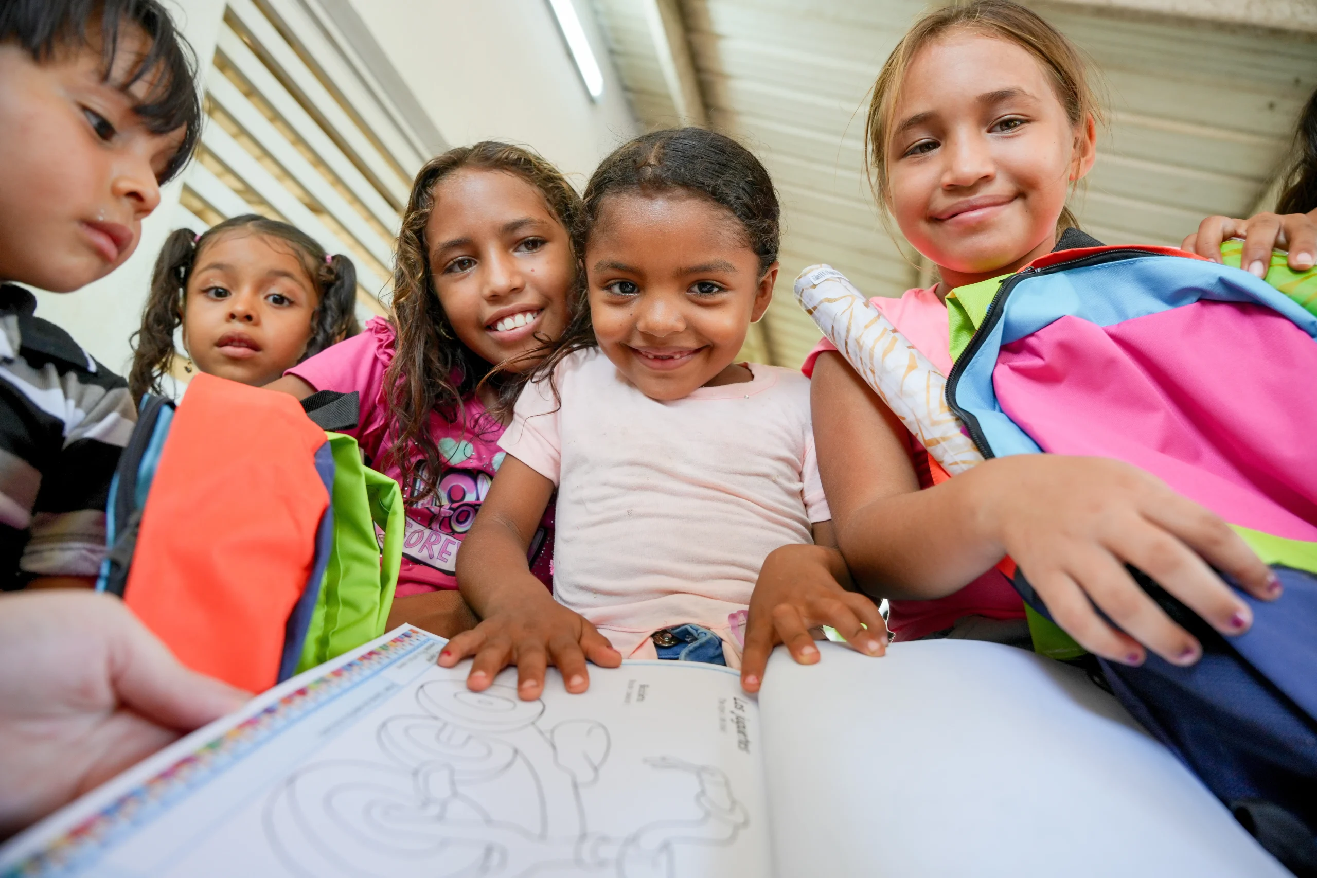 Niñas y niños muestran sus nuevos morrales y materiales escolares