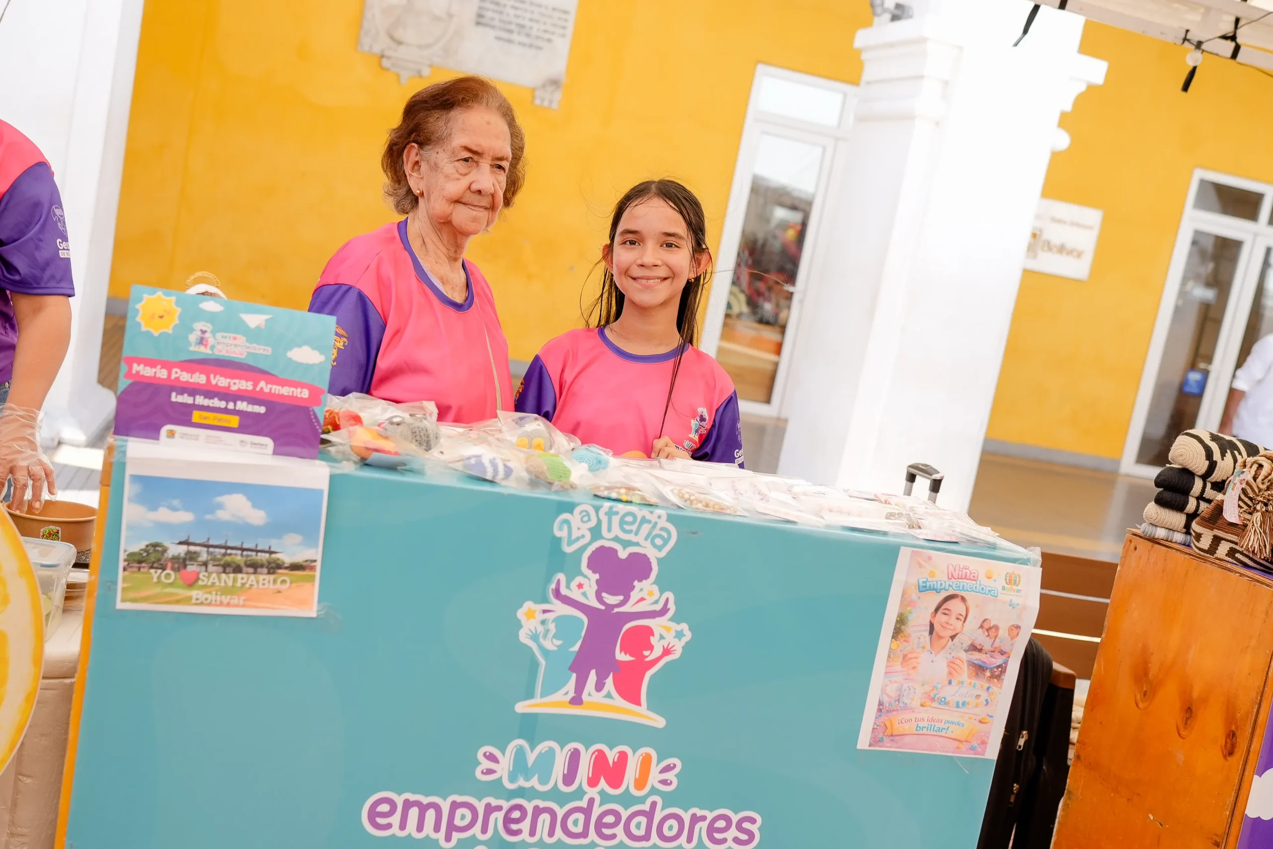 Niña y mujer atienden un puesto de productos en la feria