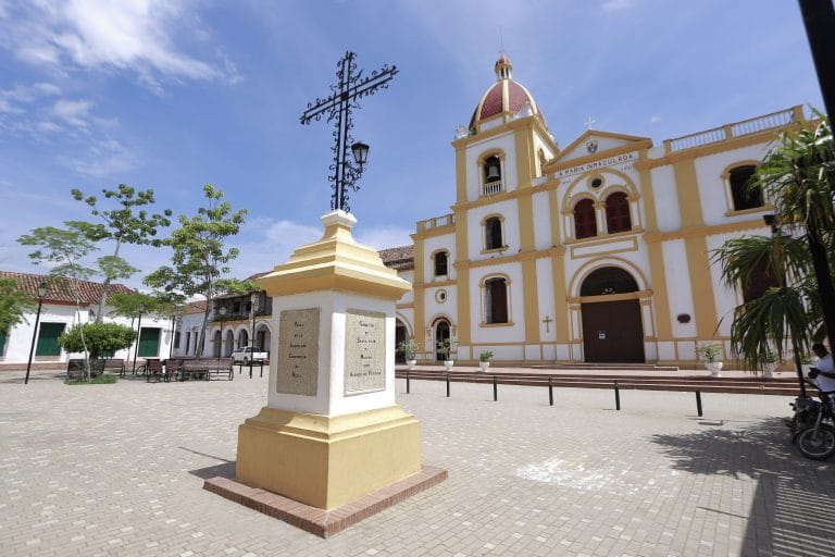 Plaza de Santa Cruz de Mompox, Bolívar, con iglesia histórica, cruz central y arquitectura colonial.