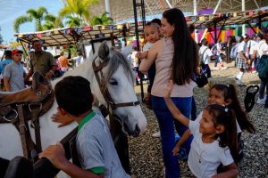 Niños y una mujer con un bebé en brazos junto a un caballo blanco durante la actividad de Panaca Viajero.