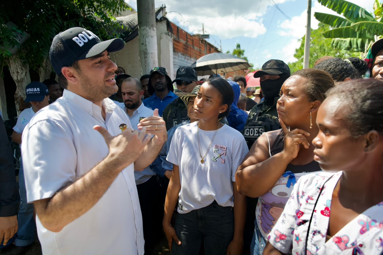 Hombre con gorra de Bolívar conversa con un grupo de habitantes de la comunidad.