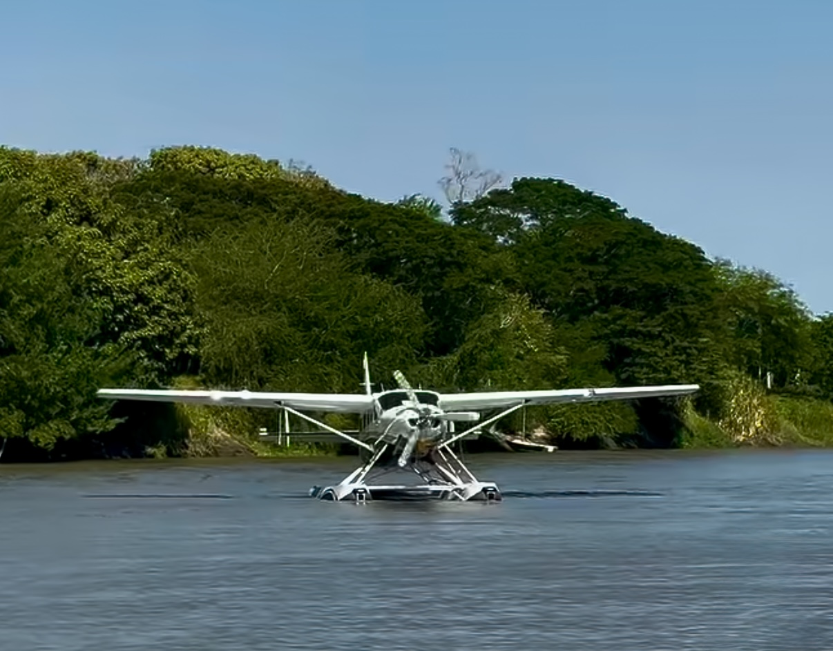 Hidroavión blanco posado sobre el río Magdalena, con vegetación de fondo.
