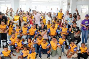 Niños, niñas y adultos con camisetas amarillas celebran durante el lanzamiento del programa.